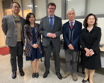 五位成員在室內合照，背景為辦公空間與落地窗；與「2025/3/20 教育學院與德國魯爾大學法學院簽署MOU」學術交流訊息相符。