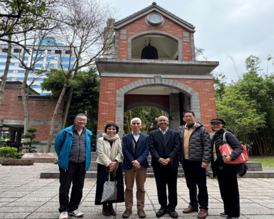六人於戶外鐘樓拱門前合照；背景有時鐘與懸掛鐘、綠植與藍白相間建物，對應「2025/3/17 教育學院 × 利仁教育基金 × Emory University Prof. Negi」國際交流。