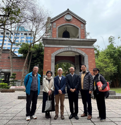 六人於戶外鐘樓拱門前合照；背景有時鐘與懸掛鐘、綠植與藍白相間建物，對應「2025/3/17 教育學院 × 利仁教育基金 × Emory University Prof. Negi」國際交流。